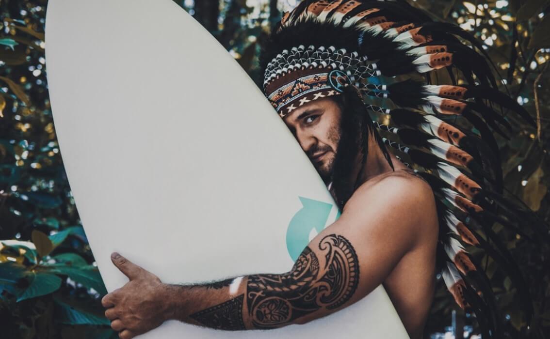 man with tattoo holding surfer